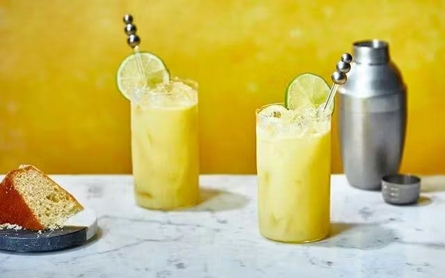 Two yellow cocktails with lime wheel garnish